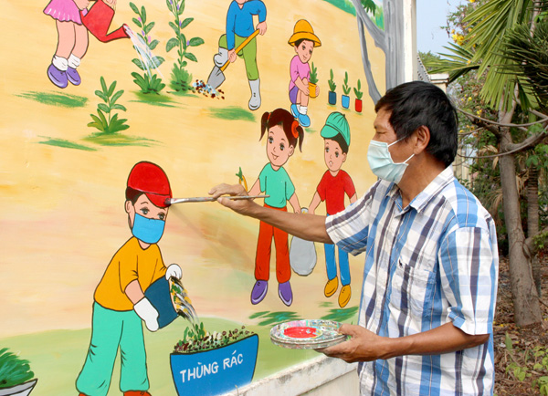 Họa sĩ Nguyễn Văn Châu vẽ tranh tường cho một ngôi trường tiểu học ở xã Vĩnh Tân (H.Vĩnh Cửu). Ảnh: L.Na