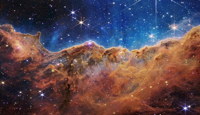 &quot;Vách đá vũ trụ&quot; của Tinh vân Carina được chụp bởi kính viễn vọng không gian James Webb. Bức ảnh được công bố ngày 12/7. Lốm đốm trên cả hai phần là một trường sao, hiển thị vô số ngôi sao với nhiều kích cỡ. (Ảnh: NASA, ESA, CSA, STScI, Webb ERO/REUTERS)