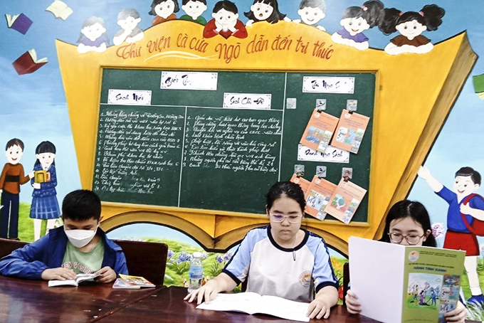 Các học sinh đọc truyện tại thư viện trường.