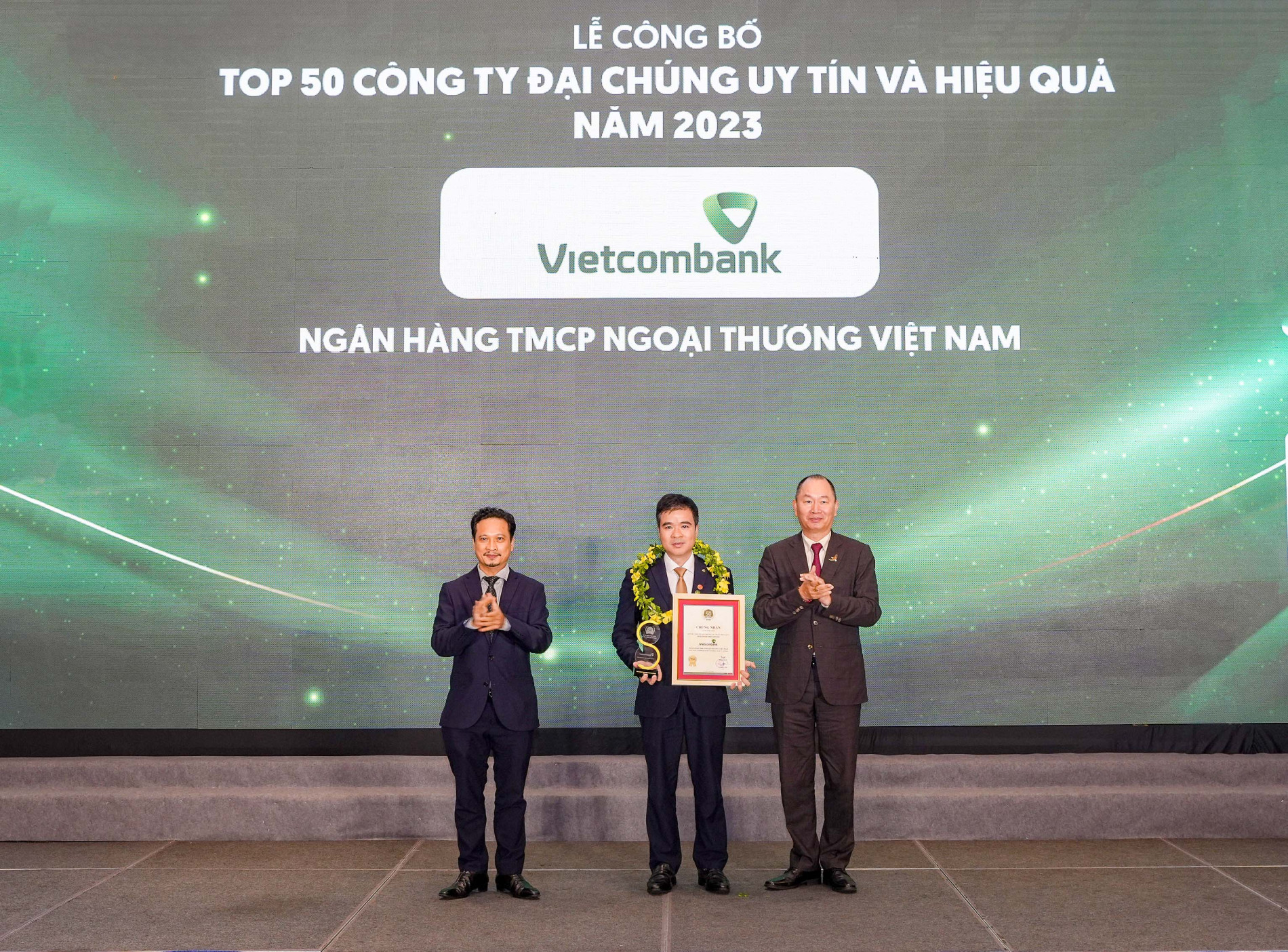 Đại diện Vietcombank (đứng giữa) nhận danh hiệu &amp;ldquo;C&amp;ocirc;ng ty đại ch&amp;uacute;ng uy t&amp;iacute;n v&amp;agrave; hiệu quả nhất Việt Nam năm 2023&amp;rdquo; từ Ban Tổ chức.