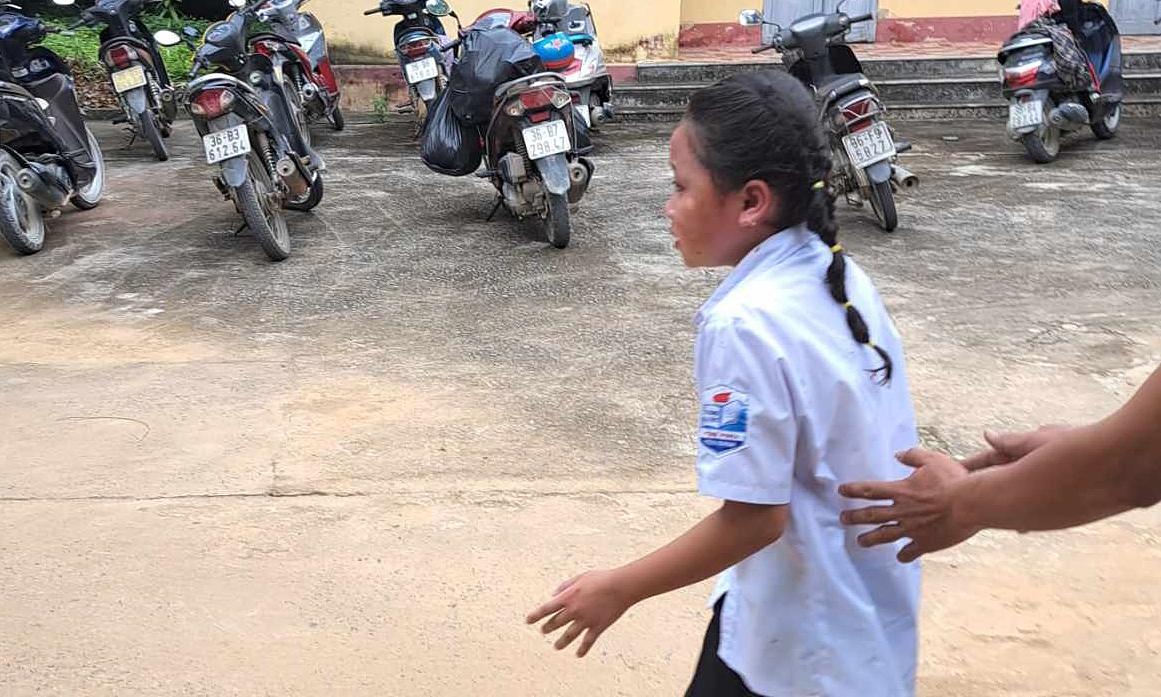 Một học sinh bị bỏng hoảng sợ được phụ huynh đưa ra khỏi sân trường sau vụ nổ bóng bay sáng 5/9. Ảnh: Lam Sơn