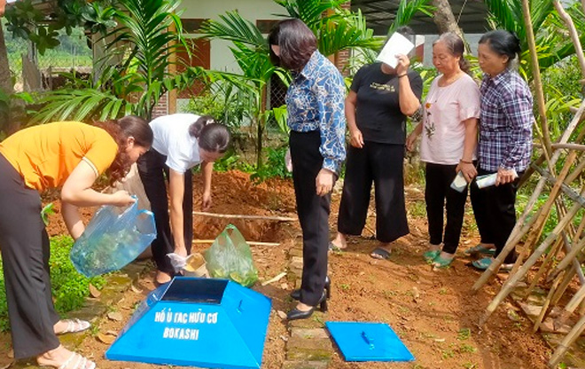 Cán bộ Hội Phụ nữ Trấn Yên hướng dẫn người dân xã Đào Thịnh ủ rác hữu cơ.