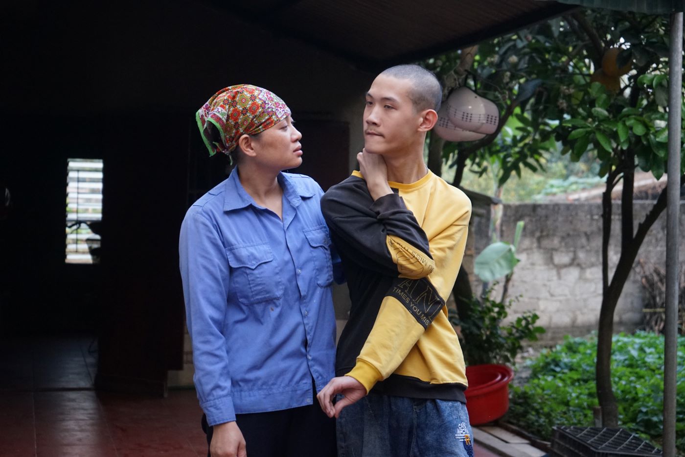 Nữ lao công Lê Thị Mai tranh thủ thời gian nghỉ chăm sóc con trai bị tàn tật. Ảnh: Quách Du