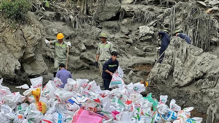 Công nhân chi nhánh dọn thủ công bùn thải sau sự cố vỡ đập hồ chứa. (Ảnh: TUẤN SƠN)